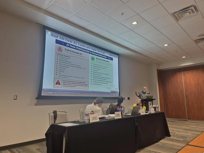 Presenter explaining a projected Gen AI teaching resource beside the seated panel.