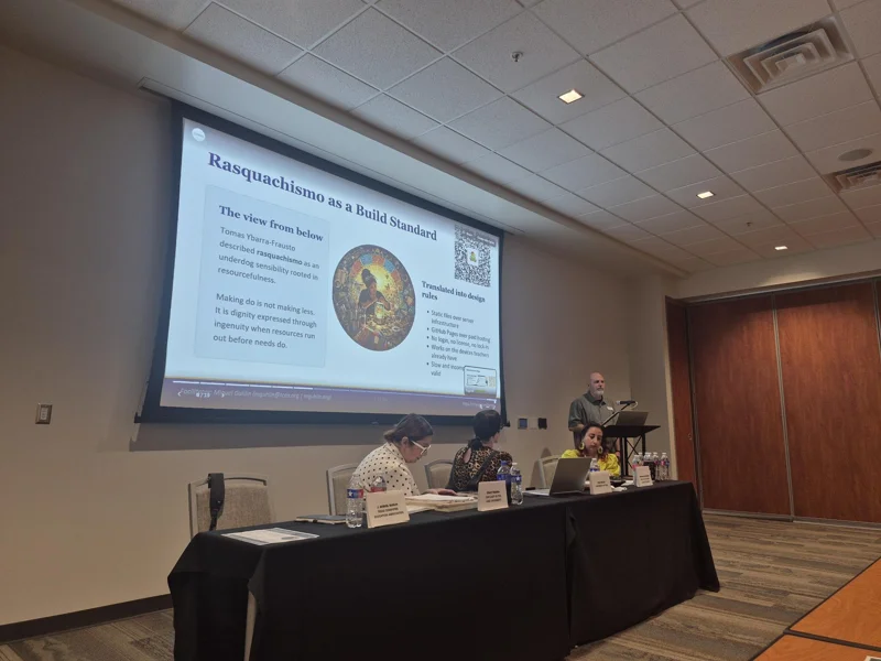 Presenter beside a Rasquachismo as a Social Strategy slide with panelists seated at the front.